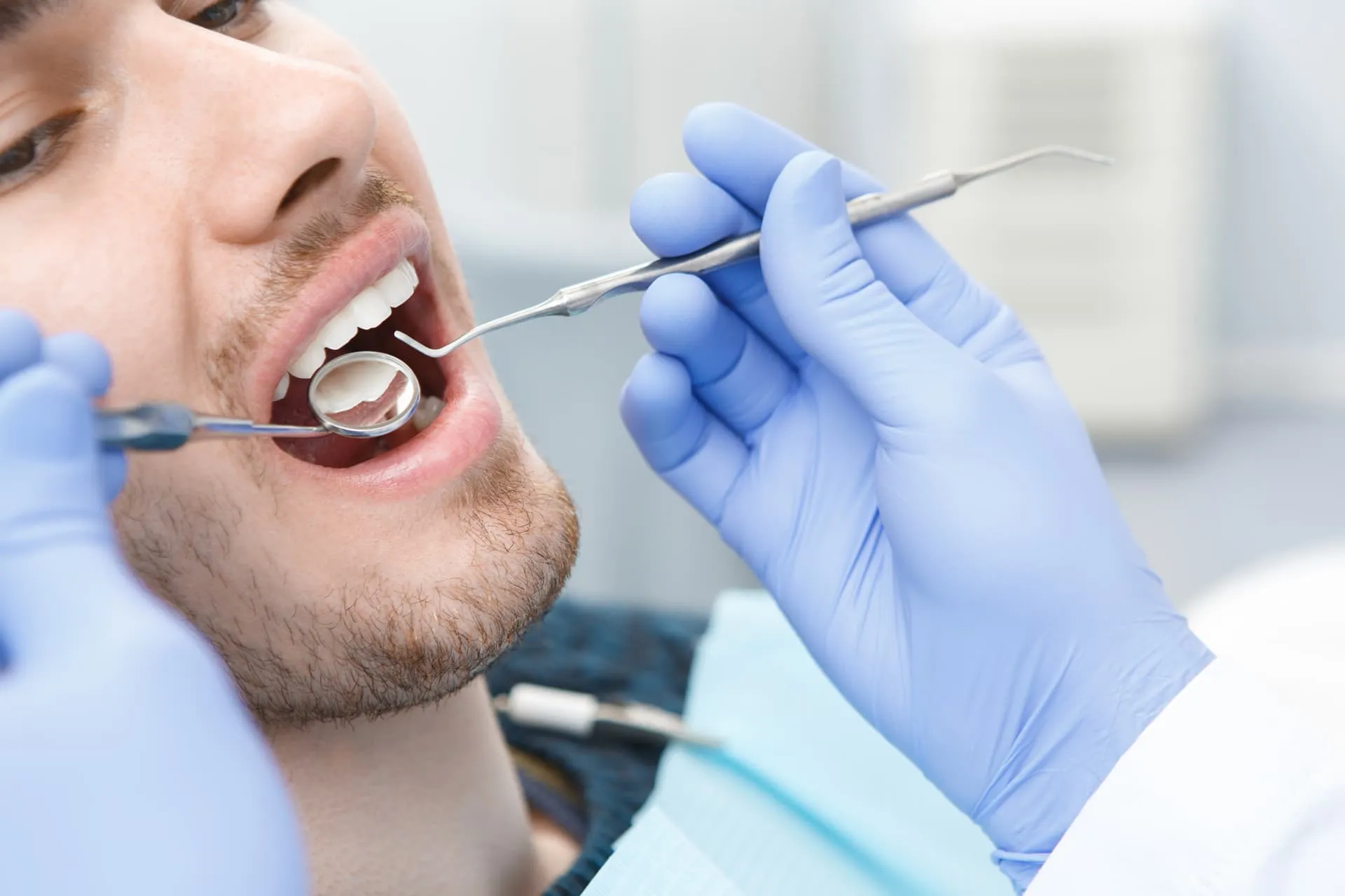 Dentista revisando la boca de un paciente con espejo y sonda