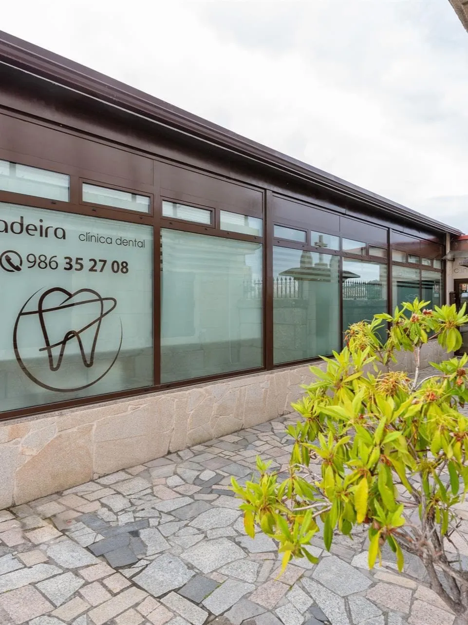 Fachada de Clínica Dental Ladeira en Sabarís con el rótulo y el teléfono de la clínica